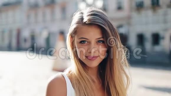 美丽的年轻女子的肖像蓝色的眼睛和迷人的微笑她站在一条街的中间视频的预览图