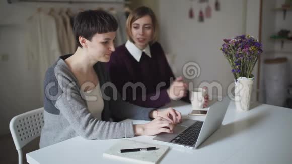 两名女学生坐在桌子上用笔记本进行在线教育视频的预览图