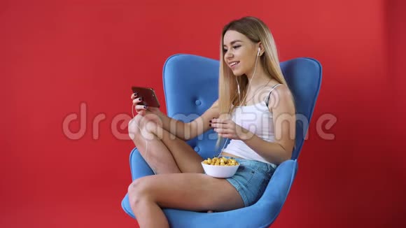 女孩坐在椅子上打电话看电影吃爆米花视频的预览图