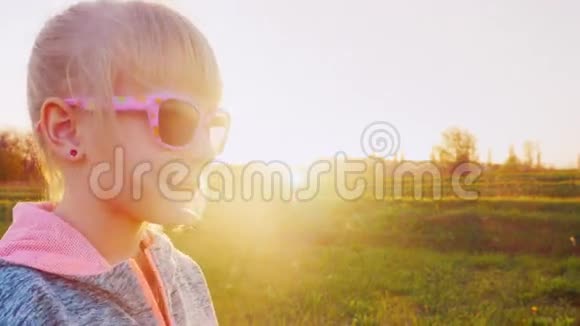 穿着运动服6岁女孩的肖像日落时分站在侧面戴着粉色太阳镜视频的预览图