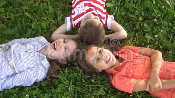 快乐的孩子们躺在草地上一起欢笑慢动作视频的预览图