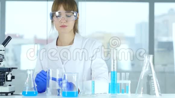 一位女科学家在烧杯中倒入化学物质用于劳动反应视频的预览图