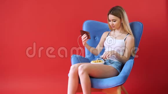 女孩坐在椅子上打电话看电影吃爆米花视频的预览图