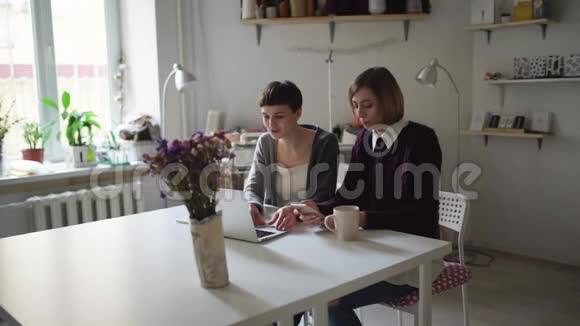 两名在桌上的女学生使用笔记本进行家庭在线学习视频的预览图