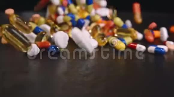 药片和彩色胶囊掉落在黑色地板上视频的预览图
