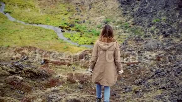 年轻的旅游妇女独自在河边的山谷散步女性探索新的地方和思考视频的预览图