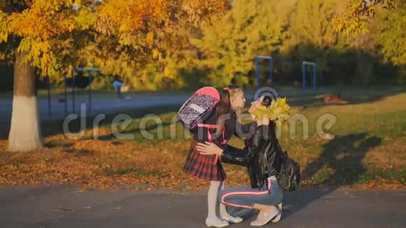 快乐的女人从学校遇到她的小女儿妈妈穿着校服拥抱和亲吻女儿慢动作视频的预览图