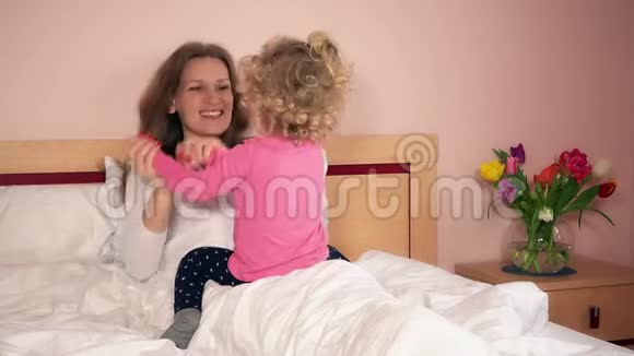 快乐的妈妈和小女儿坐在床上玩耍视频的预览图