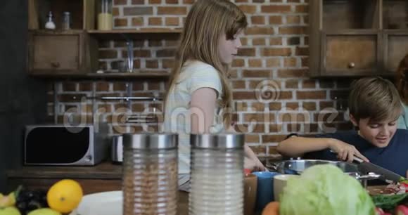 快乐的微笑父母看着孩子一起切菜在厨房家庭烹饪食物在家视频的预览图