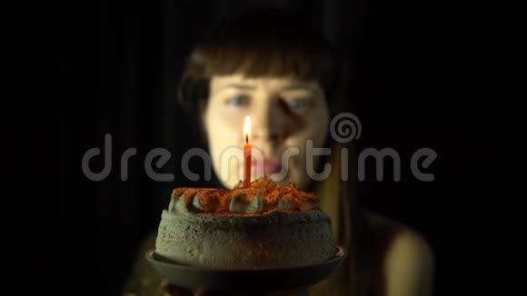 一个女人在黑色背景的蛋糕上吹灭蜡烛的特写镜头视频的预览图