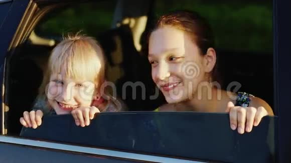 两个6岁和11岁的有趣女孩正向车窗外望去日落前的傍晚概念喜欢旅行视频的预览图
