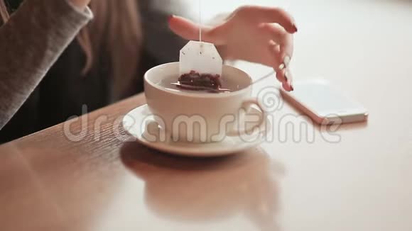 女性手拿着一杯热茶冬天咖啡馆里的女孩视频的预览图