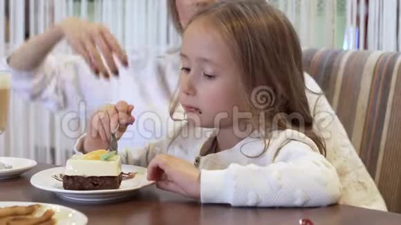 美丽的年轻母亲和小女儿一起在一间舒适的咖啡馆里吃蛋糕视频的预览图