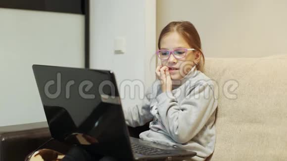 8岁女孩拿着笔记本电脑坐在沙发上剔牙视频的预览图