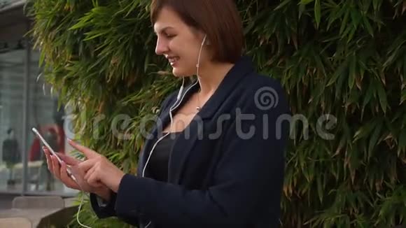 女商人用特写的脸在外面打字和听音乐视频的预览图