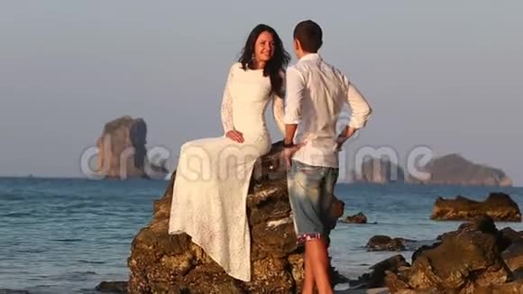 新娘坐在岩石上新郎日出时来亲吻视频的预览图