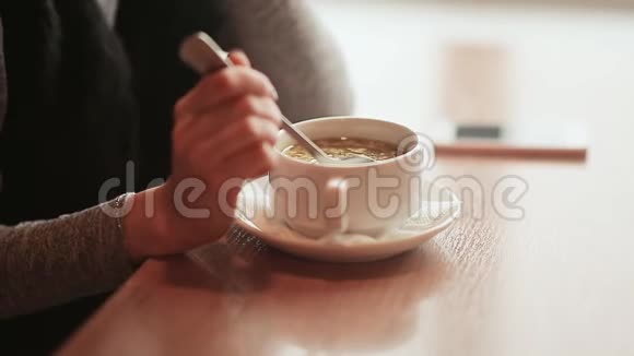 午餐休息时一个女孩坐在咖啡馆的桌子旁的手那个女孩用勺子搅拌汤冬天的时候视频的预览图