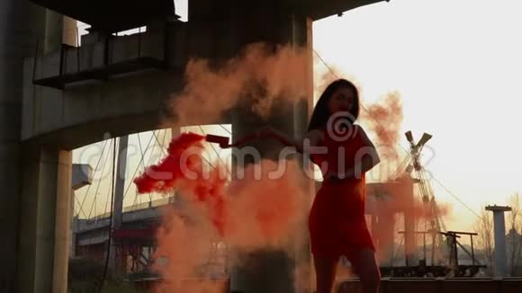 穿着红裙子的漂亮时髦女人慢镜头中带着红烟跳舞视频的预览图