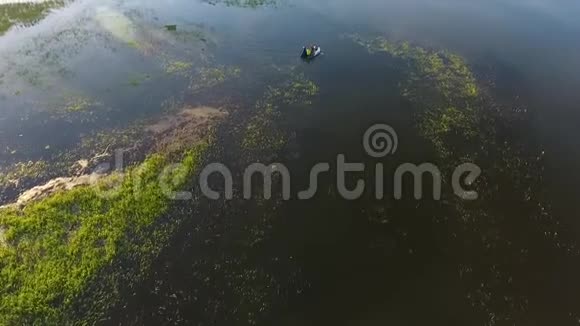 年轻的时髦朋友在夏天的湖上的充气船上划船空中高清慢镜头视频的预览图