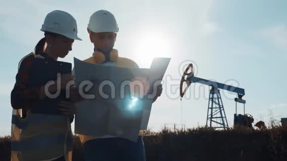 一个工程师小组正在讨论一个油田的维修问题在炼油厂工作的工程队两个工人视频的预览图