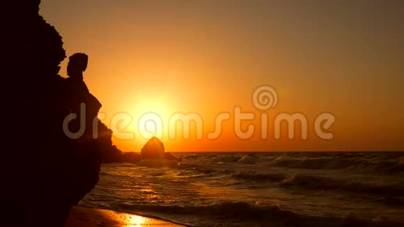 在美丽的金色日落海滩上年轻女子用手机行走的剪影高清慢速运动1920x1080视频的预览图