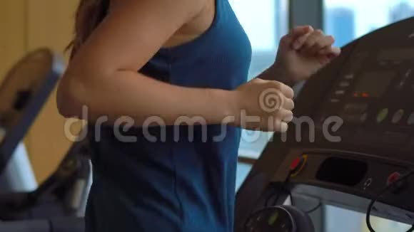 一位年轻女子在一座摩天大楼顶部的健身房里在跑步跑道上训练观看整个城市的景色视频的预览图