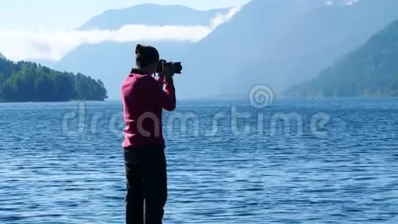 年轻女子在山上拍照在湖边拍照的女摄影师视频的预览图