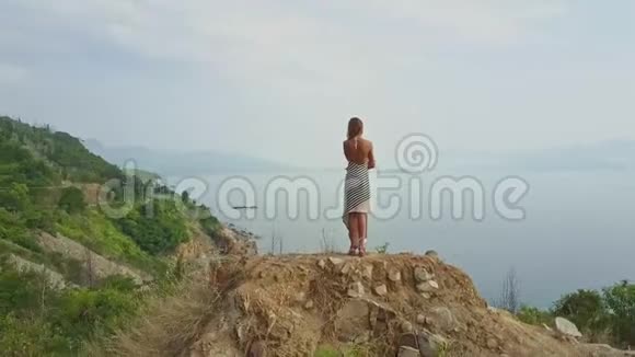 金发女孩站在高山上眺望大海视频的预览图