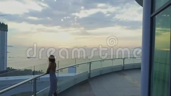 Droneview苗条女孩站在酒店顶楼与日出视频的预览图