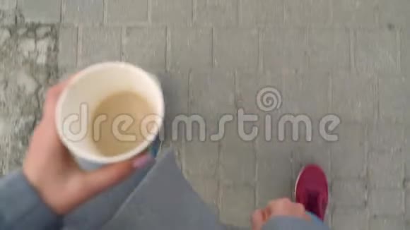 俯视男女腿漫步人行道喝咖啡的女人视频的预览图