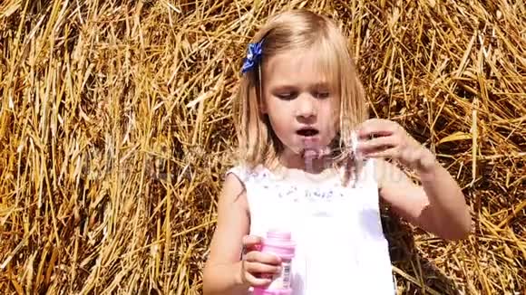 小女孩在干草的背景上吹泡泡视频的预览图