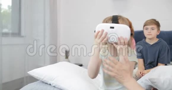 快乐的父亲在卧室里抱着戴着虚拟现实眼镜的小女孩一家人一起在家里度过早晨视频的预览图
