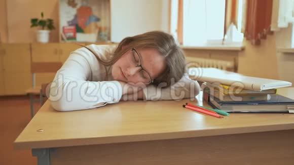 那个戴着眼镜睡在班上书上的疲倦的学生女孩视频的预览图