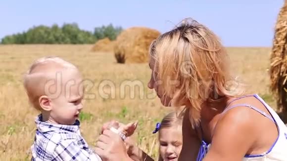 母亲在干草的背景下和儿子玩耍视频的预览图