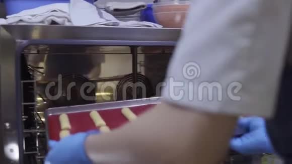 在烤箱里放一个带有蛋糕或利润的烤盘糖果店工作视频的预览图