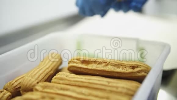 不可辨认的女糖果手戴着蓝色手套在烤盘上一排三排地铺着蛋糕视频的预览图