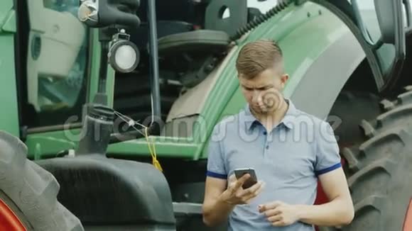 拖拉机司机在拖拉机附近使用智能手机视频的预览图