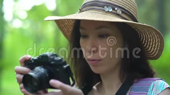 戴草帽的女孩翻着相机上的照片关于自然视频的预览图
