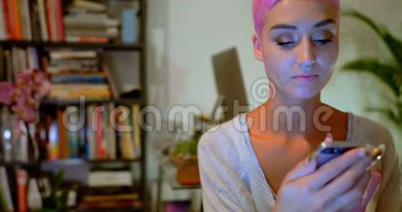 粉红头发的女人在家里用手机4k视频的预览图