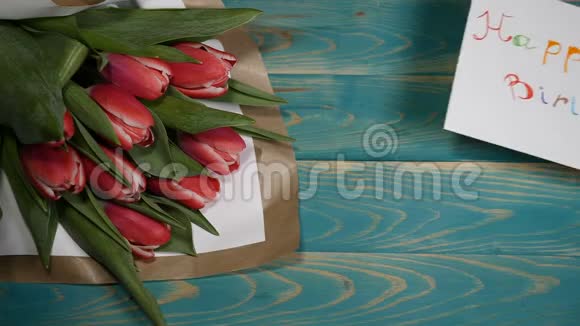 在木桌上观看生日快乐留言条和郁金香花束爱情关系概念视频的预览图
