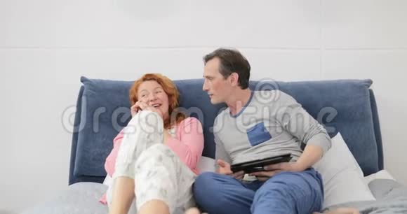 男人和打电话的女人聊天幸福的家庭夫妻躺在床上视频的预览图