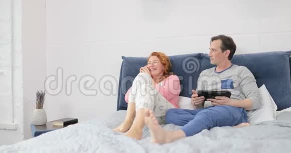嫉妒的男人看着正在打电话的女人笑着坐在床上夫妻卧室视频的预览图