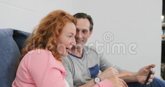 使用手机的成年夫妇躺在床上孩子们在卧室里和家人一起玩耍视频的预览图