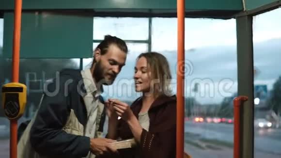年轻的幸福夫妇站在公共交通工具里坐电车女人带着票去运输男人在等着视频的预览图