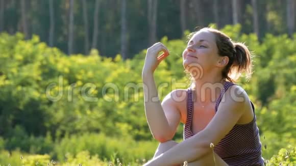 幸福的微笑女人在夕阳下的风景田野上的青草上啜泣视频的预览图