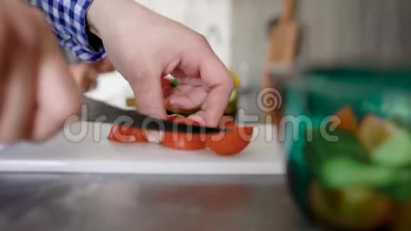一个无法辨认的人站在厨房的桌子上在砧板上切番茄视频的预览图