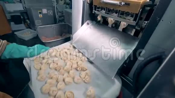 肉汤圆从工厂的机器上落到一个托盘上工人正在摇晃它们视频的预览图