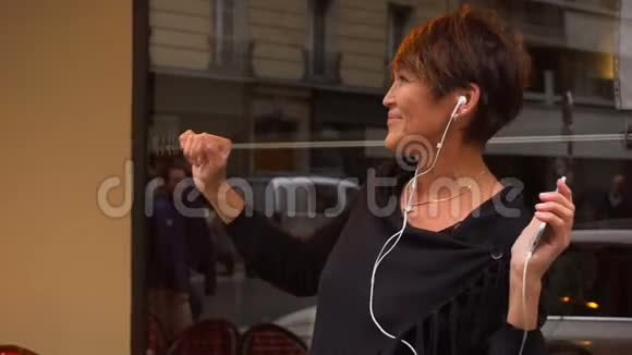 慢动作中年女性游客通过智能手机听音乐跳舞视频的预览图