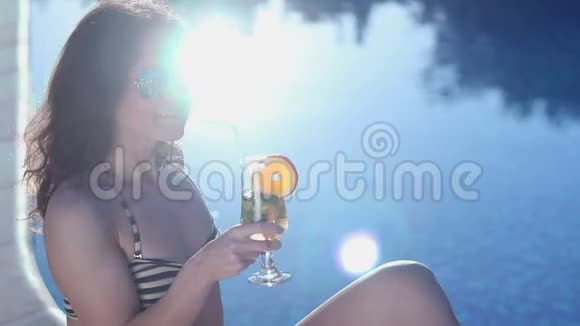 快乐的女孩喝鸡尾酒游泳池里阳光明媚视频的预览图