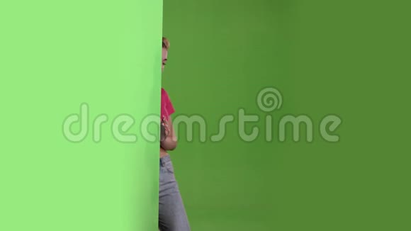 青少年从一块绿色的木板后面偷看竖起大拇指绿色屏幕视频的预览图